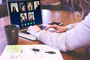 Frau sitzt vor einem Laptop und nimmt an einem Online-Seminar teil.