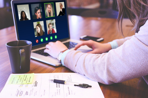 Frau sitzt vor einem Laptop und nimmt an einem Online-Seminar teil.