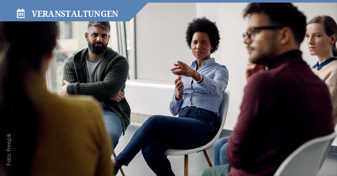 Gruppe diverser Menschen sitzen in einem Stuhlkreis und diskutieren