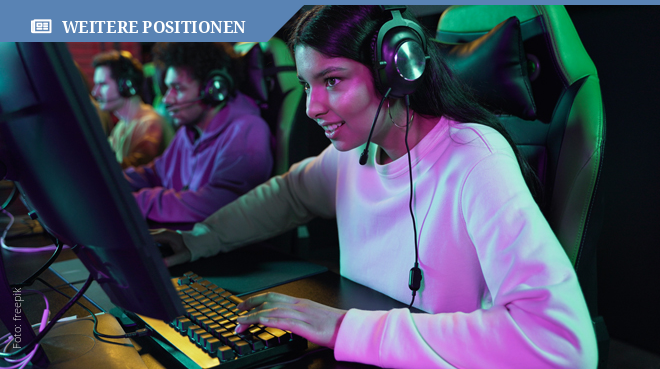 Mädchen sitzt vor einem Computerbildschirm und trägt einen Kopfhörer auf dem Kopf